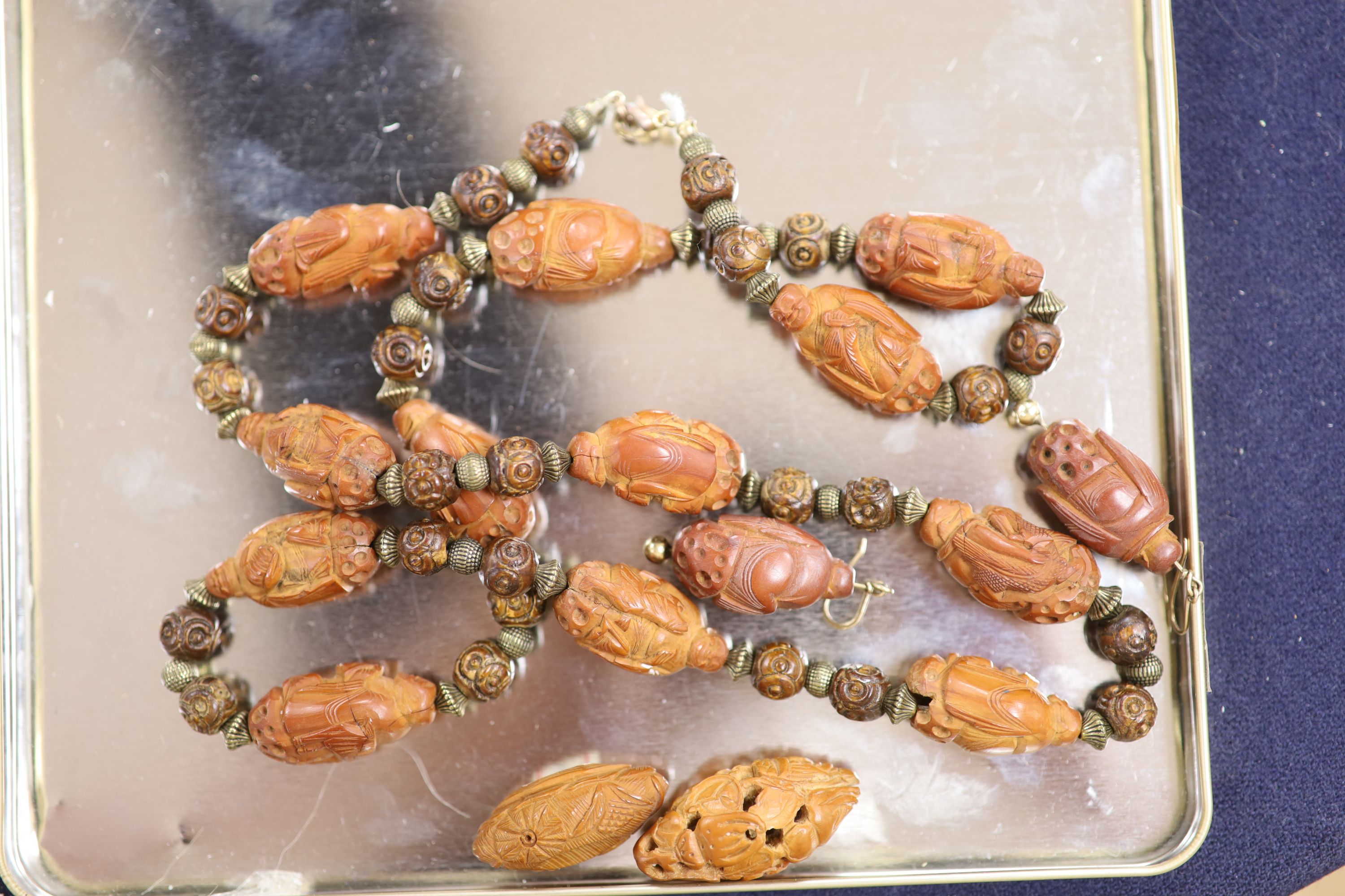 A Chinese peach stone or nut bead necklace, bracelet, a pair of earrings and two carved beads